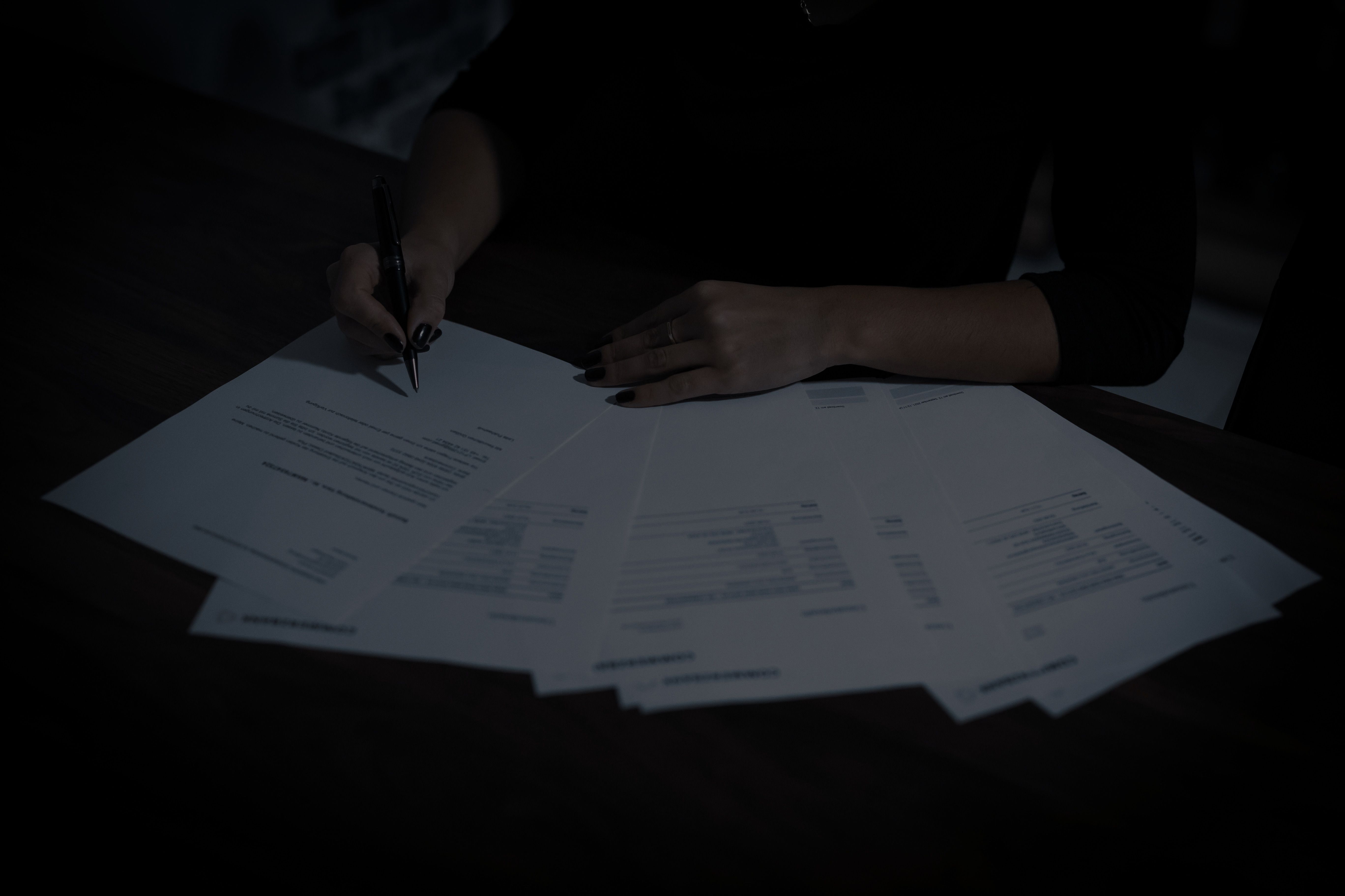 O persoană verifică documente tipărite, cu pixul în mână
